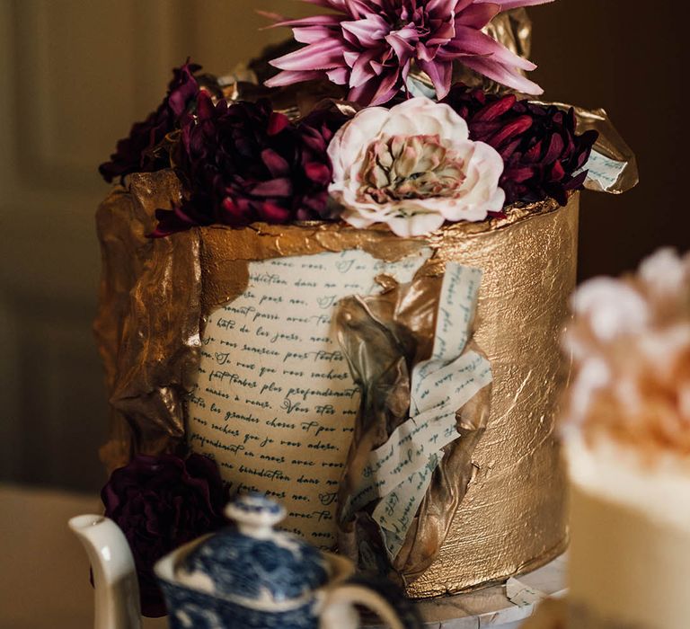 Gold iced wedding cake with newspaper print icing with purple flower decorations