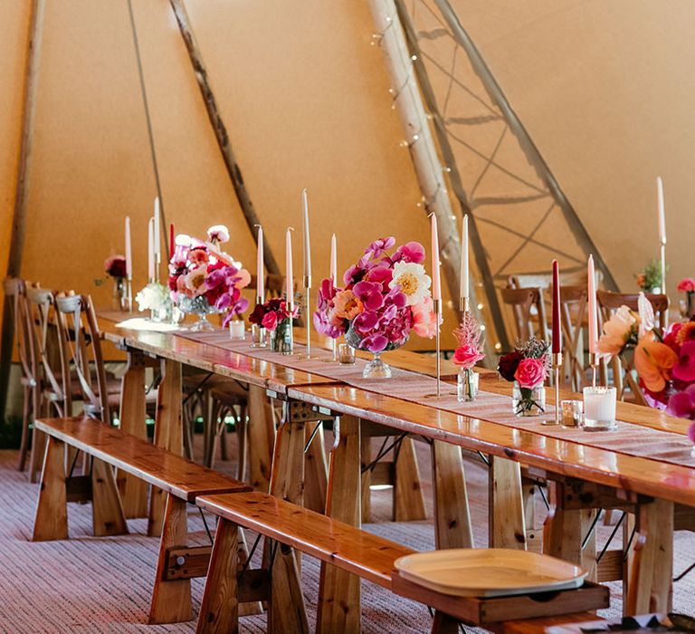 Pink, peach and white wedding taper candles with flower table arrangements at tipi wedding