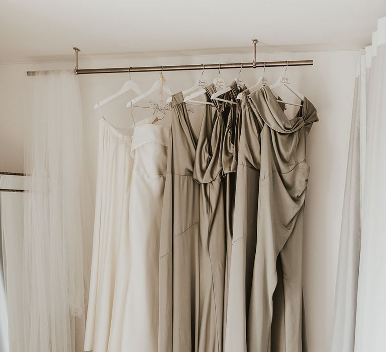 Bride's Eva Lendel wedding dress hanging next to golden multiway bridesmaid dresses 