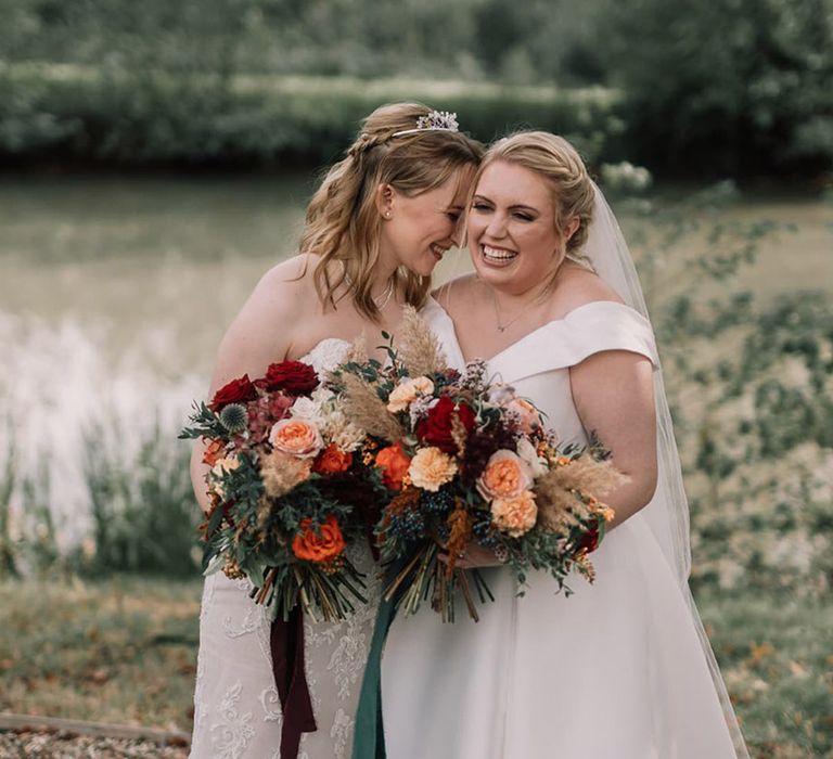 Red rose and pampas grass wedding bouquet held by two brides 