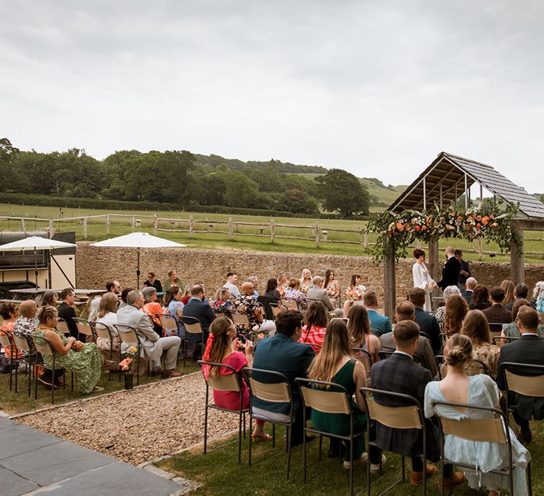 Hope Farm in Dorset outdoor wedding ceremony with colourful orange wedding flowers and pampas grass decorations 