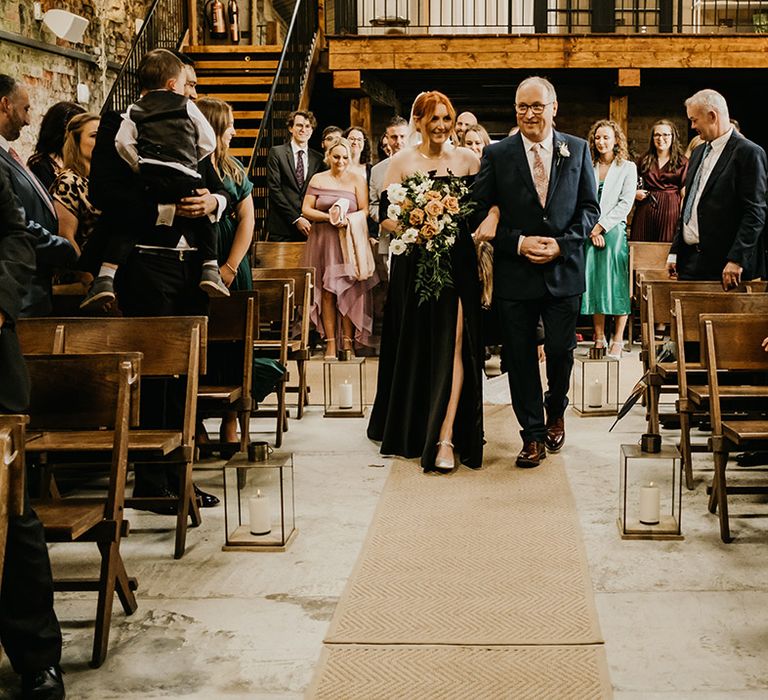 Rustic wedding ceremony with the father of the bride walking the bride down the aisle lined with lanterns 