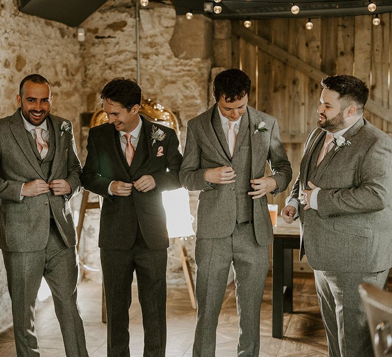 Groomsmen in matching light grey suits standing with the groom 