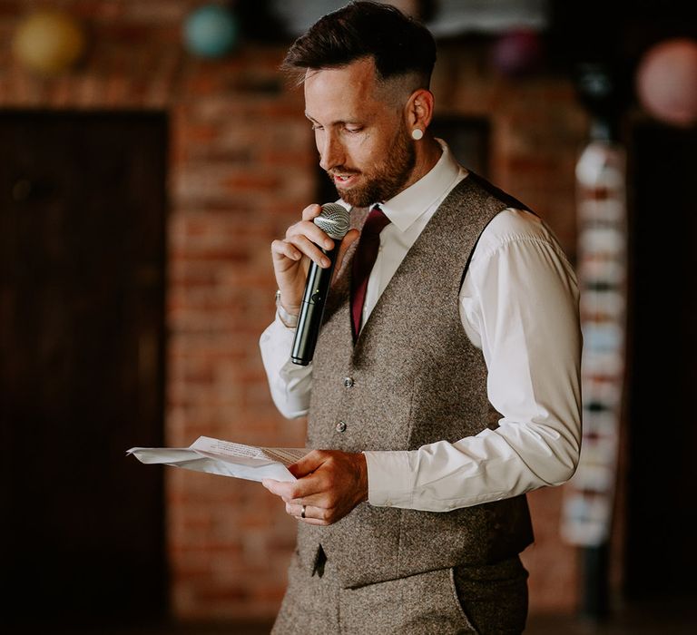 Groom stands with a microphone to read out his wedding speech 