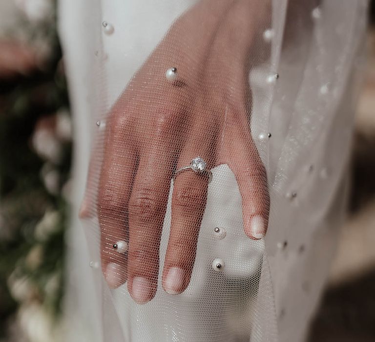 Bride wearing diamond engagement ring with pearl bridal veil 