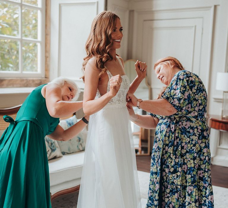 The bridal party and family members help the bride get ready for the wedding 