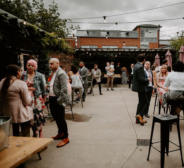 Wedding guests stand outside mingling at The Shack Revolution industrial wedding venue 