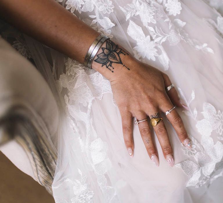 Bride wearing gold signet ring and dainty silver rings with evil eye nail art design 