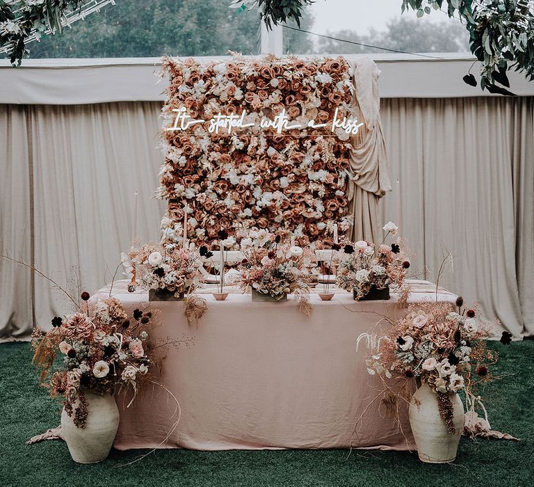 Romantic pink sweetheart table with flower wall and neon sign at marquee wedding breakfast 