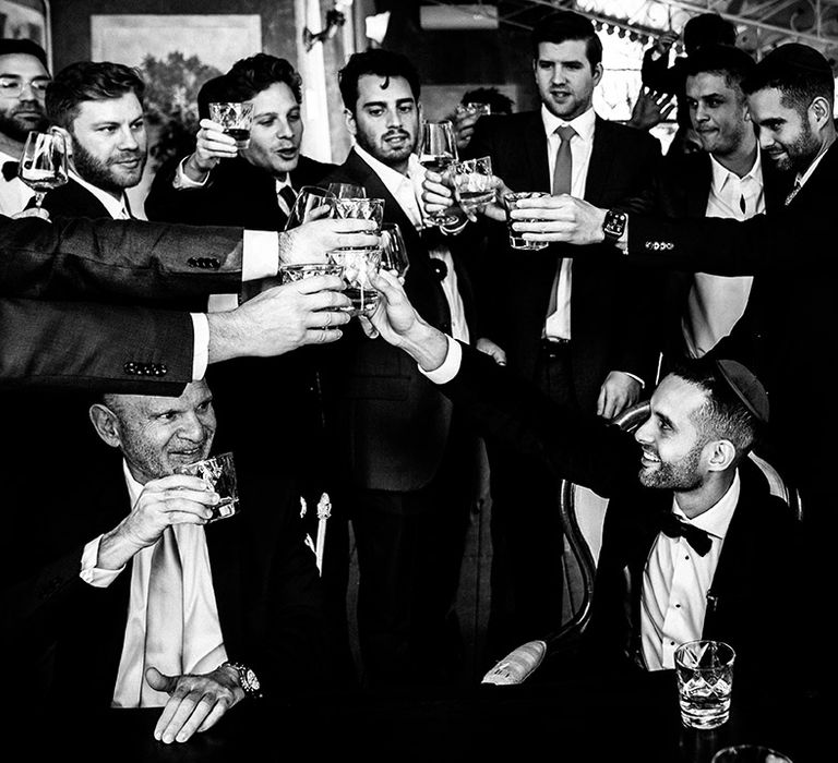 The groom and male wedding guests share drinks together 