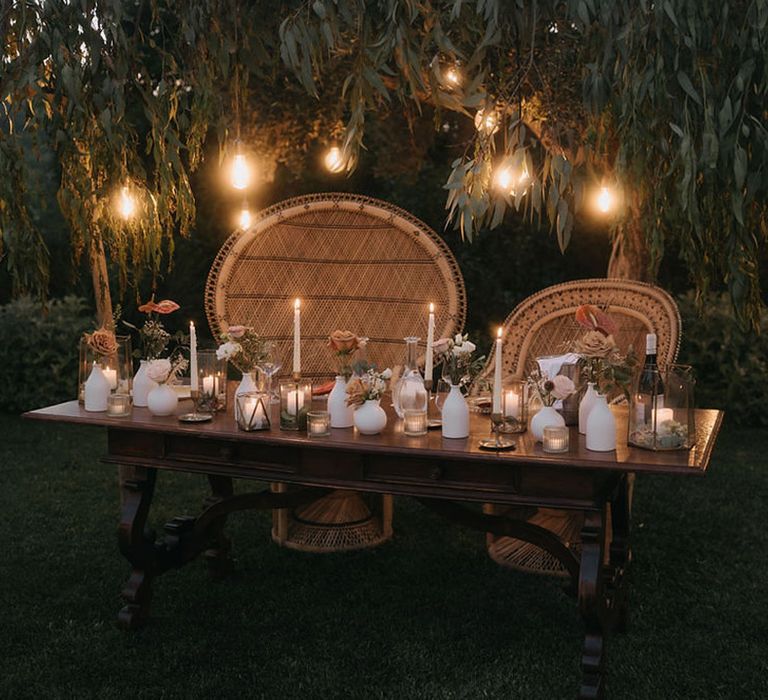 Rustic sweetheart table with peacock chairs and festoon lighting 