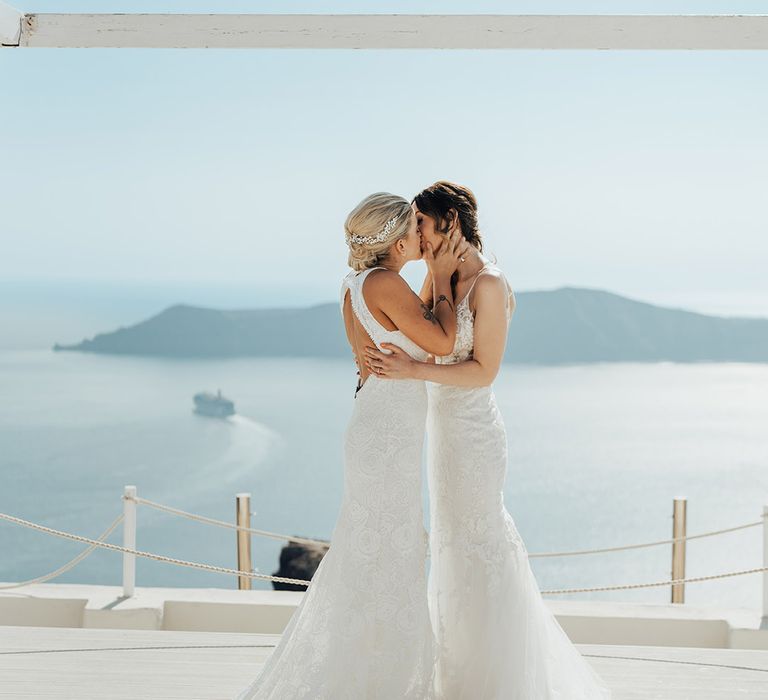 Two brides in boho lace wedding dresses share their first kiss as a married couple for lesbian wedding 