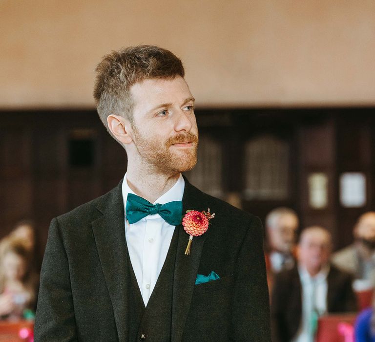 Groom in three piece black wedding suit with dark green wedding tie and pocket square with dahlia buttonhole 