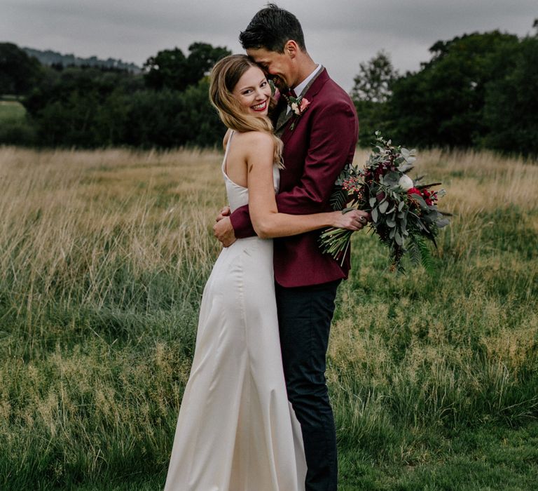 Bride and groom embracing in a field at High Billinghurst Farm micro wedding