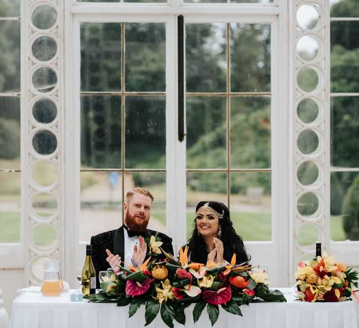 Bride and groom sitting at their wedding reception sweetheart table