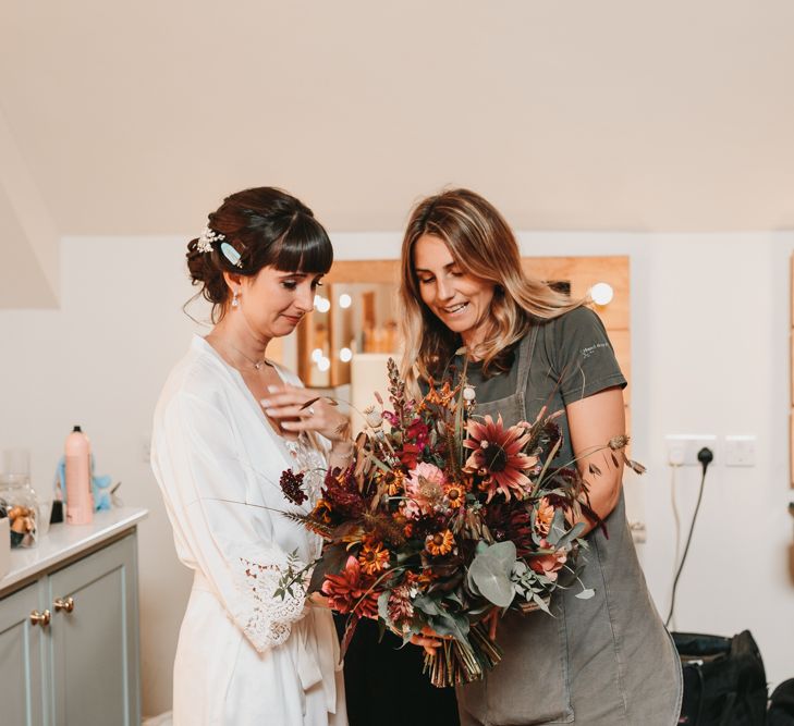 Bride on the wedding morning looking at her autumn wedding bouquet 