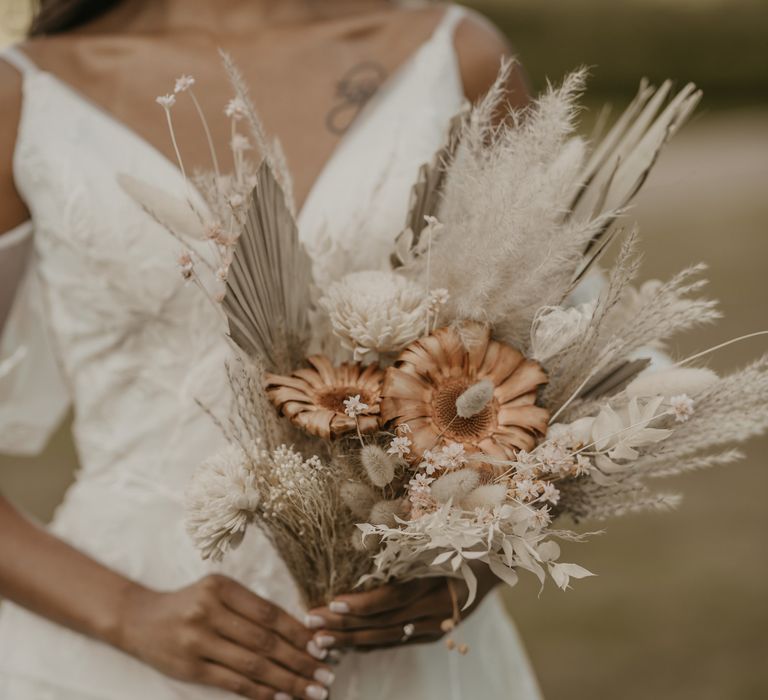 Bride holding a blush and neutral dried grass and flower bouquet 