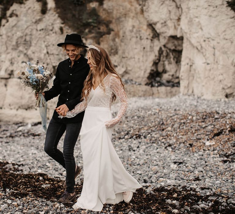 Stylish coastal elopement with bride in trainers and groom in hat 