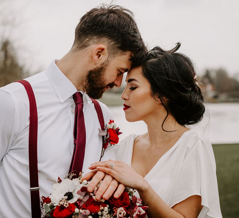 Bride with anemones bouquet by lake with Groom