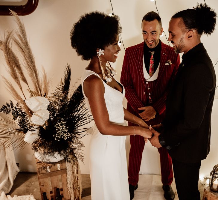 Bride in trousers and top with groom in black suit