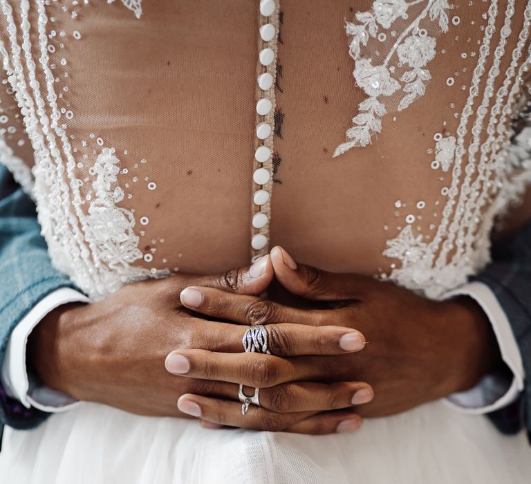 Groom's hands interlocking around the bride's button up Pronovias gown