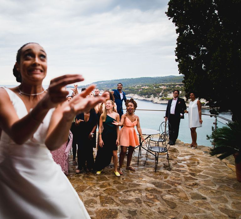 The bride laughing as her bouquet lands in the crowd at her Chateau wedding in South of France