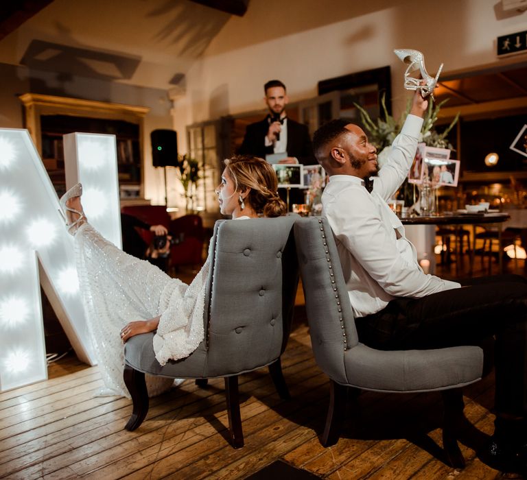 Bride and groom playing the Mr and Mrs game with each others shoes at Hampton Court House wedding