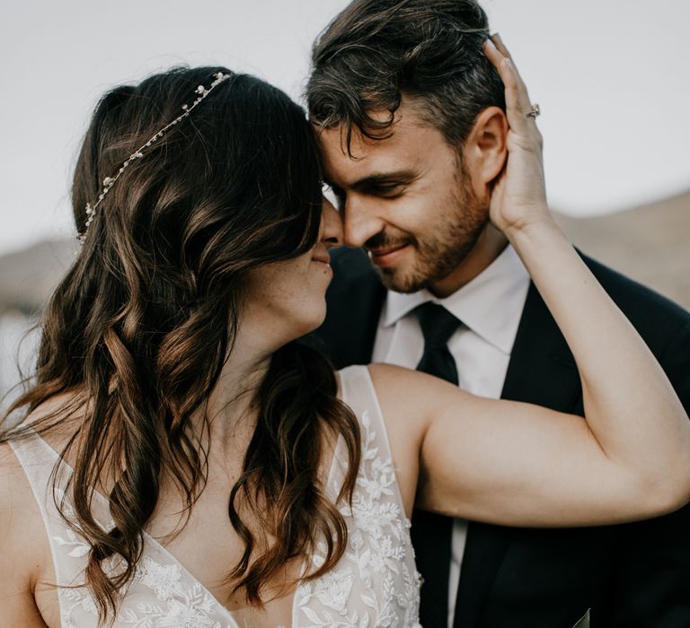 Bride reaches hand behind her to groom 