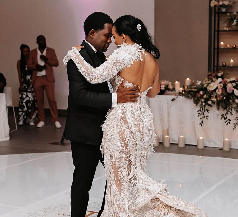 Bride and groom first dance with bride in a Biji La Maison de Couture wedding dress with feathers and separate arm sleeve