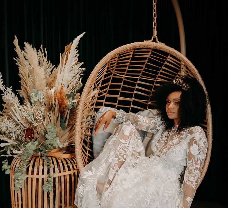 Bride leans back in wicker chair next to pampas grass bouquet 