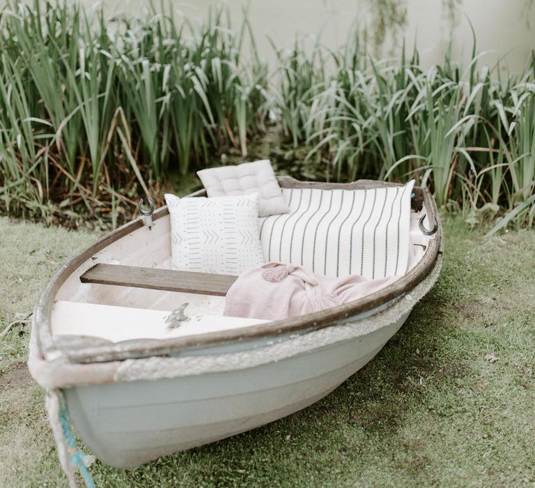 A white rowboat next to an algae covered lake