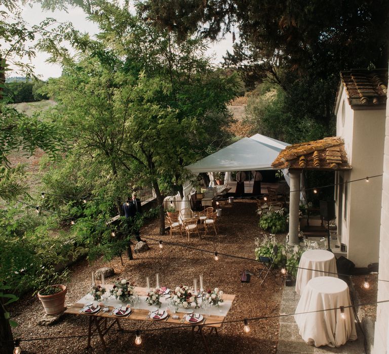 Outdoor rustic Italian wedding complete with fairy lights and wooden tables set in the countryside