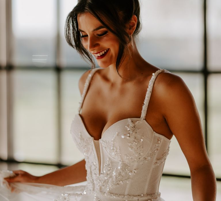 Bride in an embellished corset wedding dress with loose bridal bun wedding hairstyle 