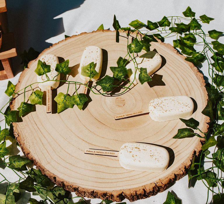 Cake popsicles resting on a tree slice surrounded by ivy