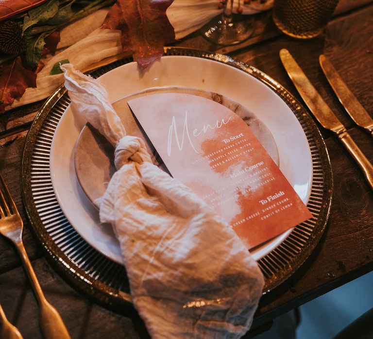 Linen table napkins, watercolour wedding stationery and gold cutlery for pumpkin spice wedding tablescape