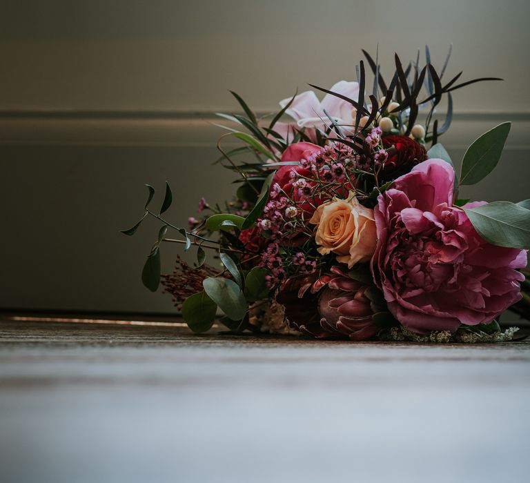 Floral bouquet in bright pink and reds with green foliage for bride