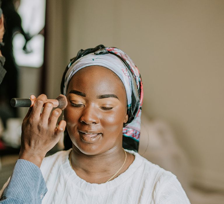 Black bride has her eye makeup done on the morning of her wedding day