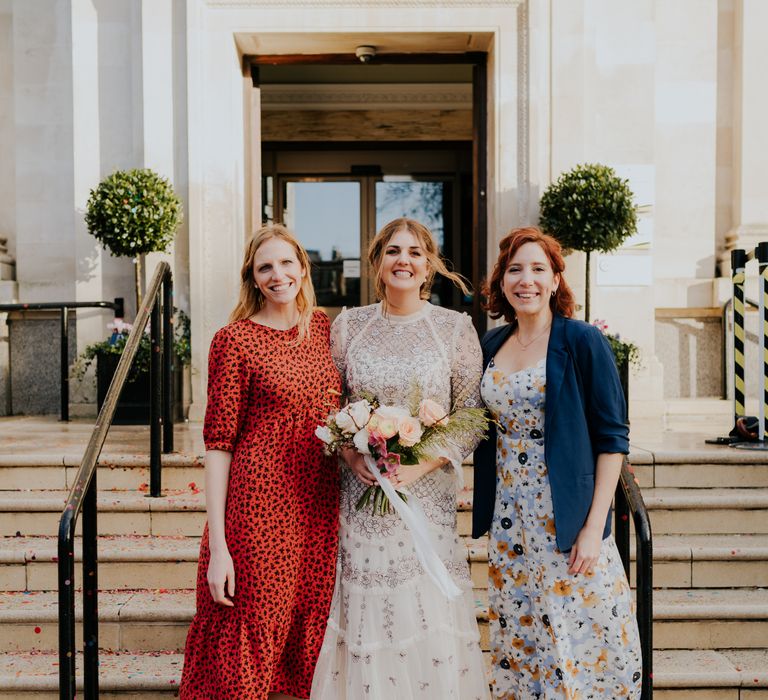 Bride stands with wedding guests on the steps of town hall after wedding ceremony