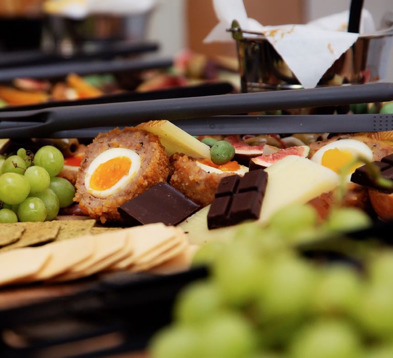 Crackers, scotch egg and grapes on wooden board for grazing table