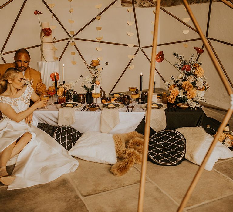 Intimate wedding reception on the floor with cushions under a wooden geoframe 