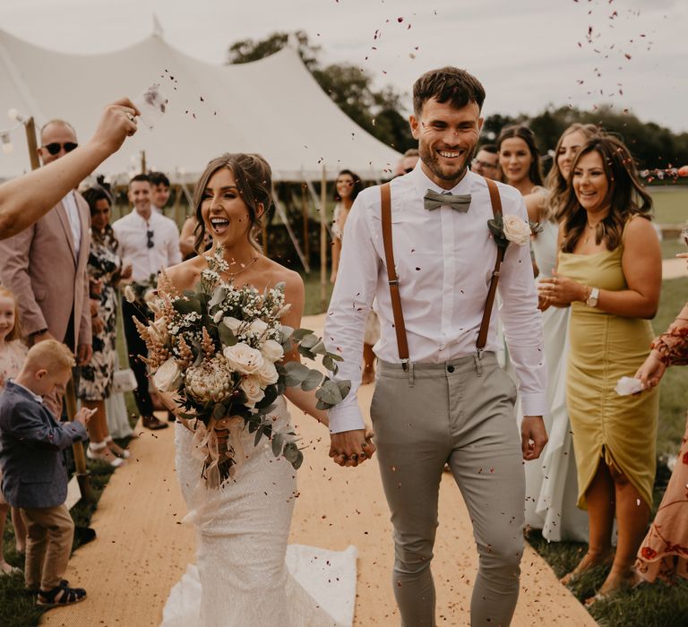 Bride & groom walk down the aisle at Duddon Mill Farm as wedding guests throw confetti around them | Mark Bamforth Photography