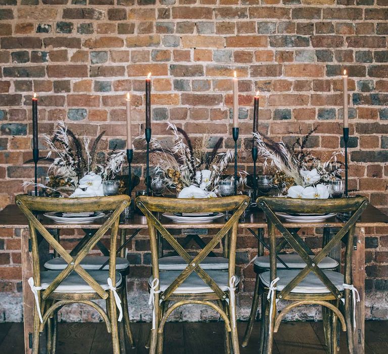 Intimate wedding reception with wooden chairs, dried flowers and coloured candles 