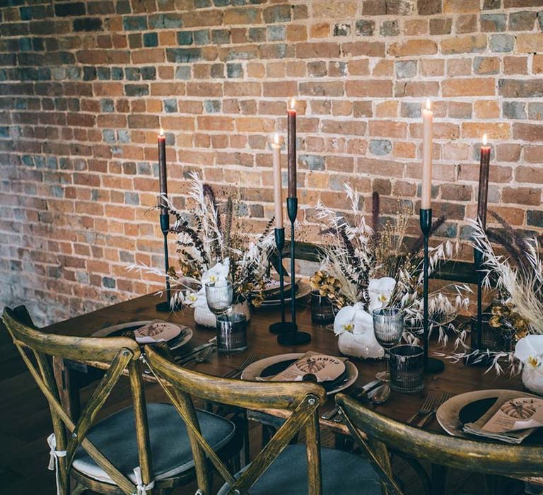 Intimate wedding table decor with wooden chairs, taper candles and dried flower centrepieces 