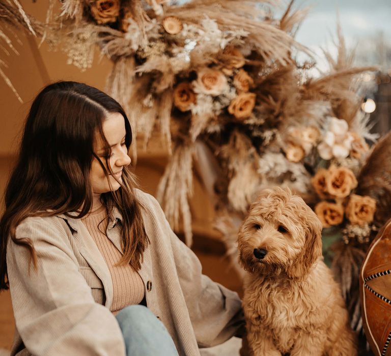 Bride in jeans and Dr Martens sitting with her pet Cockapoo at her boho bell tent marriage proposal 