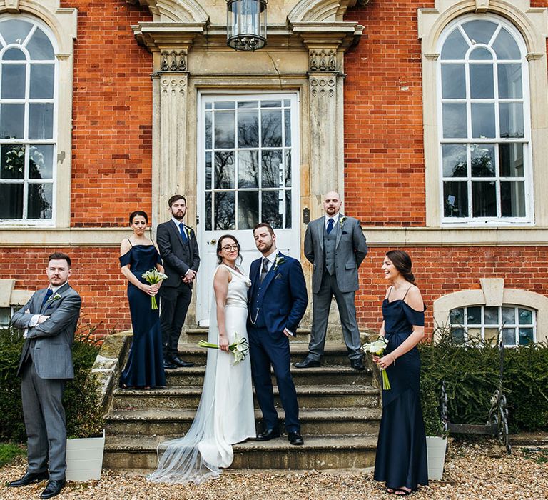 bride & groom stand with their wedding party outdoors on grand staircase