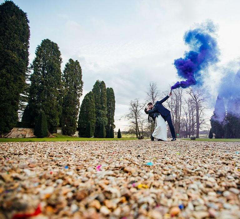 Bride & groom let off purple and blue smoke bomb outdoors