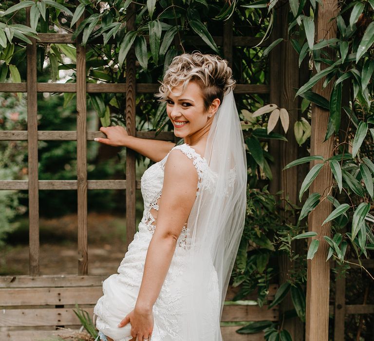 Bride smiles and shows off garter on the day of her wedding