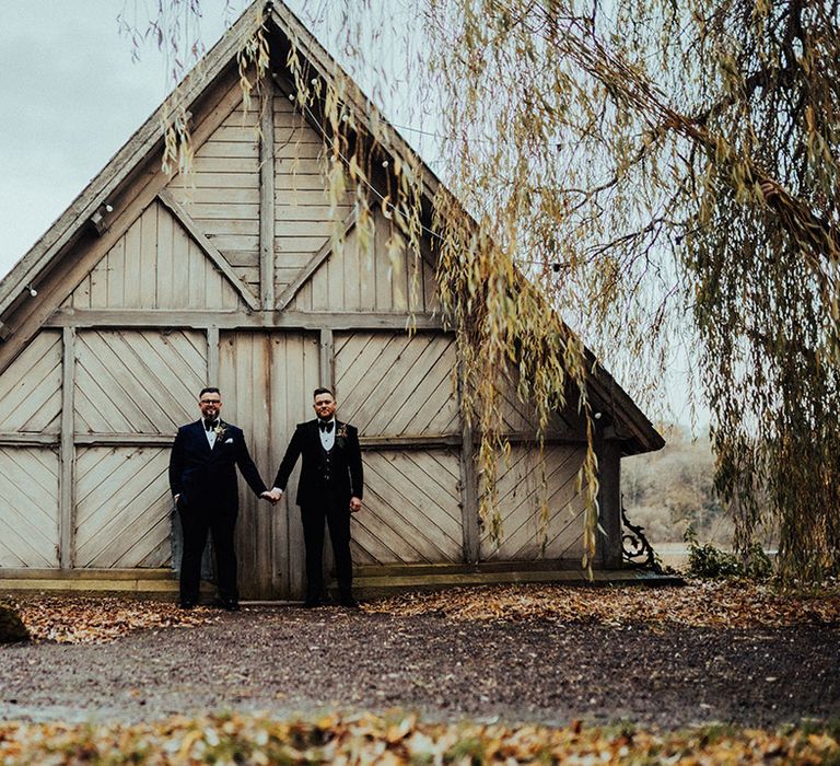 Castle Leslie Estate wedding venue with grooms standing holding hands together after their wedding 