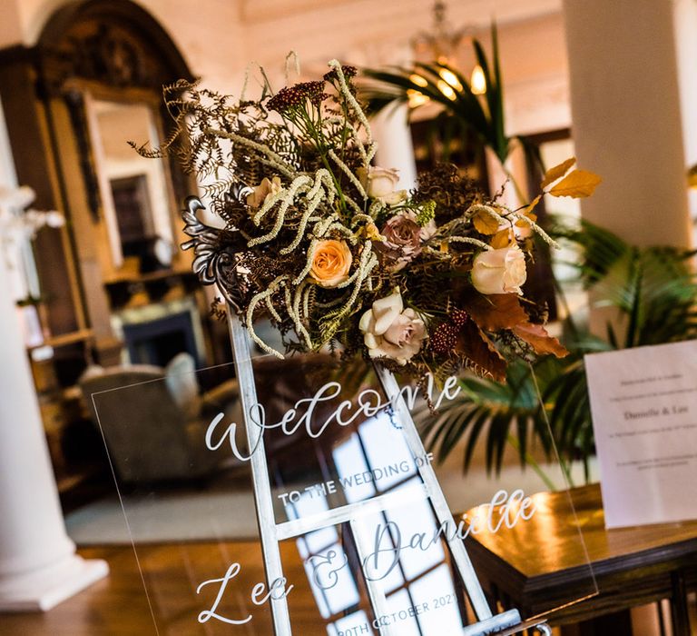 Clear welcome wedding sign with silver font on silver decorative easel with autumnal toffee and beige rose wedding bouquet 