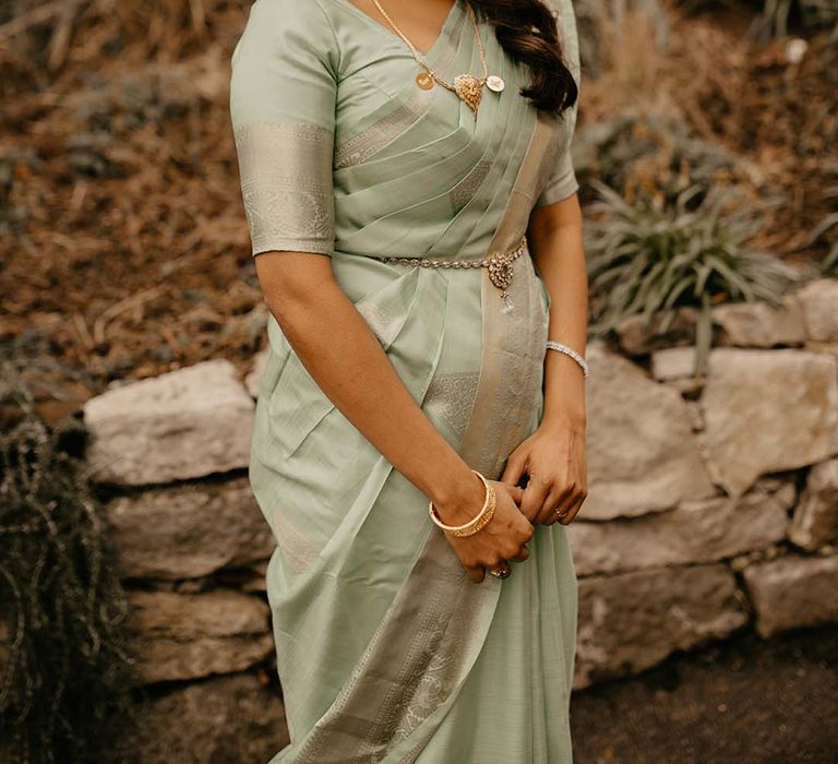 Bride in mint green saree with golden and pearl jewellery and golden embellishments at The Petersham Hotel